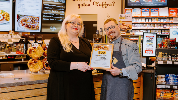 Bernd Fischer, Account Manager Foodservice bei Lekkerland, überreicht Swetlana Stoll, Geschäftsführerin des Autohofs in Rappenau, eine Urkunde für den 500. Standort mit Fresh + Tasty.