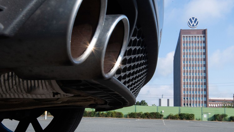 VW-Dieselskandal: Neues Großverfahren startet im November  Auspuffrohre eines Volkswagen, fotografiert mit dem Markenhochhaus am VW-Werk Wolfsburg im Hintergrund.